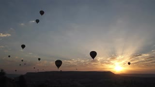 wide-shot-of-silhouetted-hot-air-balloons-drifting-in-the-sky-at-sunrise_4dmpsu3og__S0000